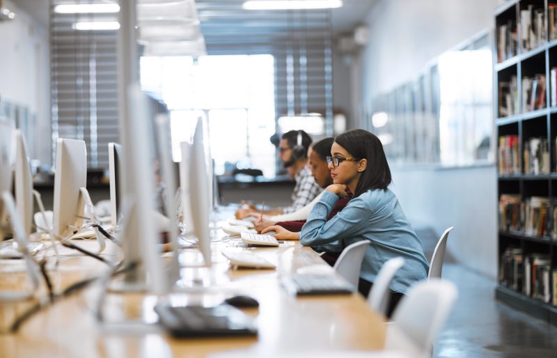 Shot of a group of university students working on computers in the library at campus